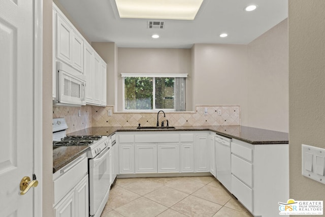 kitchen featuring tasteful backsplash, white appliances, dark stone counters, sink, and white cabinetry