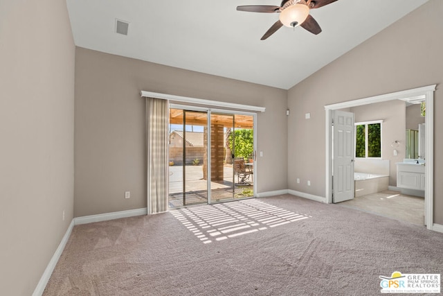 empty room featuring light carpet, ceiling fan, vaulted ceiling, and a wealth of natural light