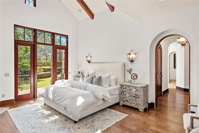 bedroom featuring hardwood / wood-style floors, access to exterior, beamed ceiling, and high vaulted ceiling