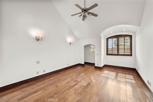 empty room with hardwood / wood-style flooring, ceiling fan, and high vaulted ceiling