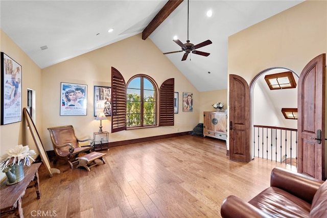 living area featuring ceiling fan, light hardwood / wood-style flooring, high vaulted ceiling, and beamed ceiling