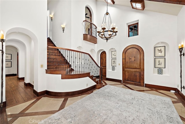 entrance foyer with high vaulted ceiling, dark wood-type flooring, and a notable chandelier