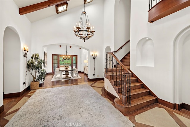 entryway with beam ceiling, an inviting chandelier, high vaulted ceiling, and hardwood / wood-style flooring