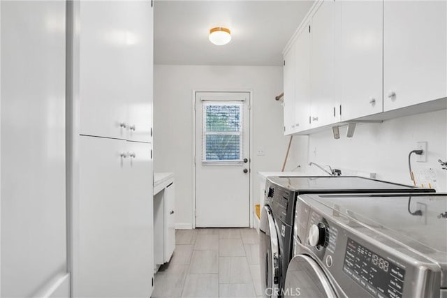 clothes washing area with cabinets and independent washer and dryer