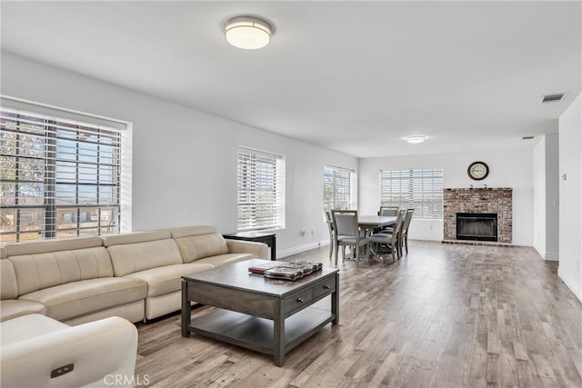 living room featuring a brick fireplace and light hardwood / wood-style flooring