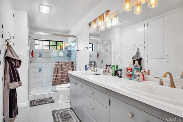 bathroom featuring tile patterned flooring, a shower with door, vanity, and toilet