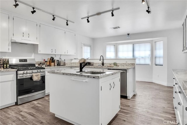 kitchen with light hardwood / wood-style floors, white cabinetry, an island with sink, and appliances with stainless steel finishes