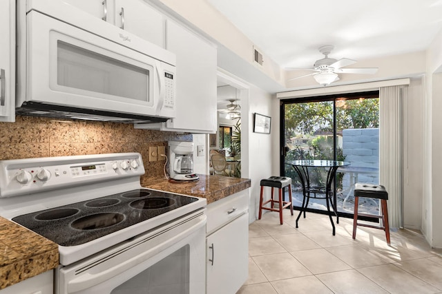 kitchen with white cabinets, light tile patterned flooring, backsplash, and white appliances