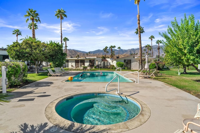 view of swimming pool featuring an in ground hot tub, a yard, a patio area, and a mountain view