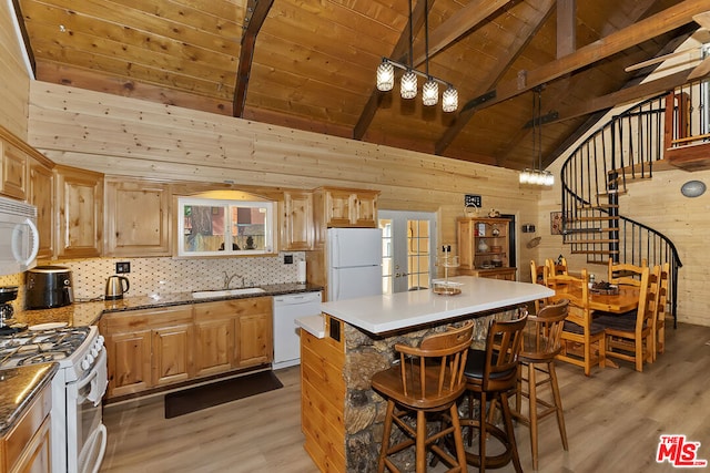 kitchen with light wood-type flooring, wood walls, white appliances, and a center island