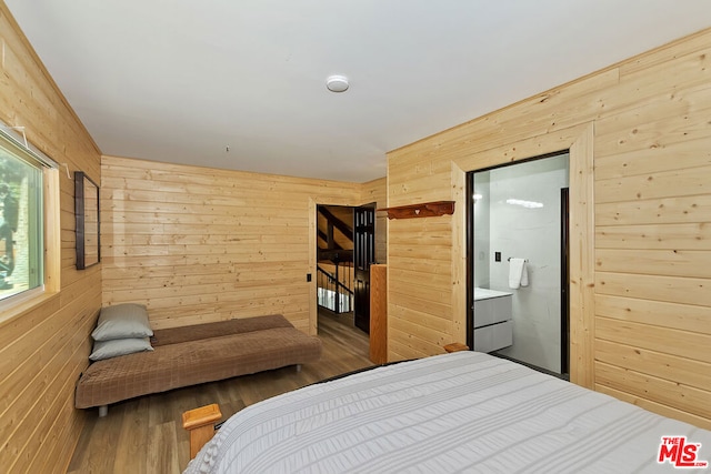 bedroom with wood walls, hardwood / wood-style floors, and ensuite bathroom