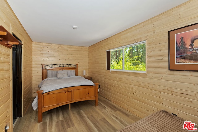 bedroom featuring wood walls and wood-type flooring