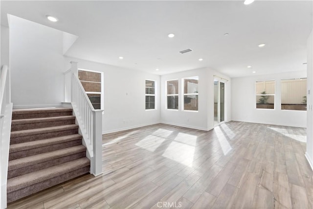unfurnished living room featuring light wood-style flooring, baseboards, visible vents, recessed lighting, and stairs