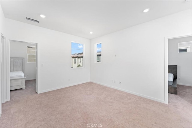 unfurnished bedroom with light carpet, baseboards, visible vents, recessed lighting, and a walk in closet