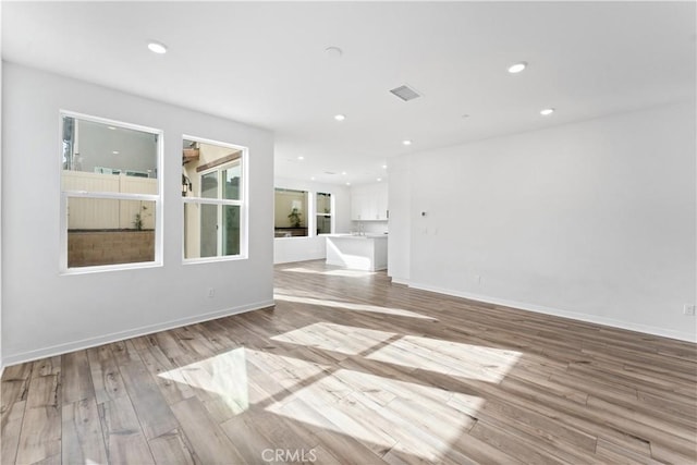 unfurnished living room featuring baseboards, light wood-style flooring, visible vents, and recessed lighting