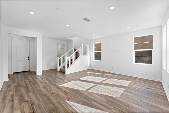 unfurnished living room featuring recessed lighting, wood finished floors, visible vents, and baseboards