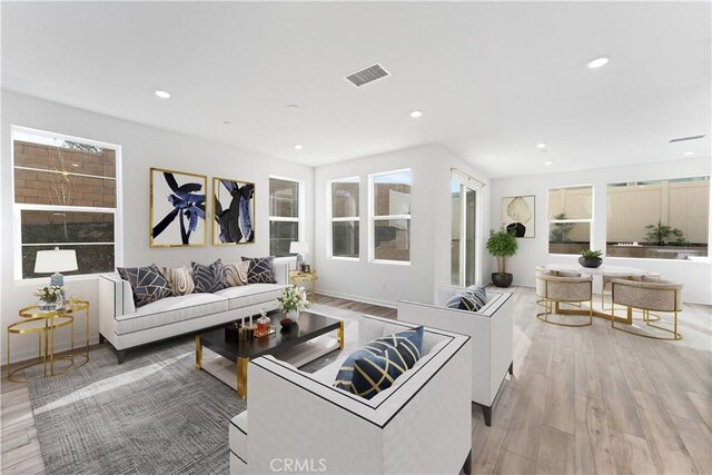 living room featuring light wood-type flooring, visible vents, and recessed lighting