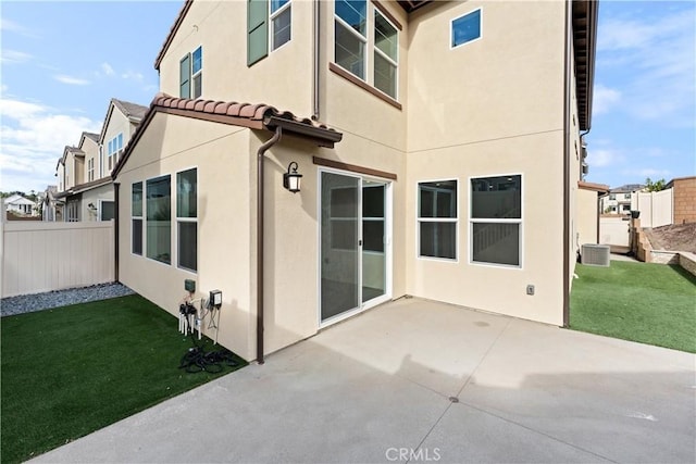 back of property with central AC unit, a yard, and a patio