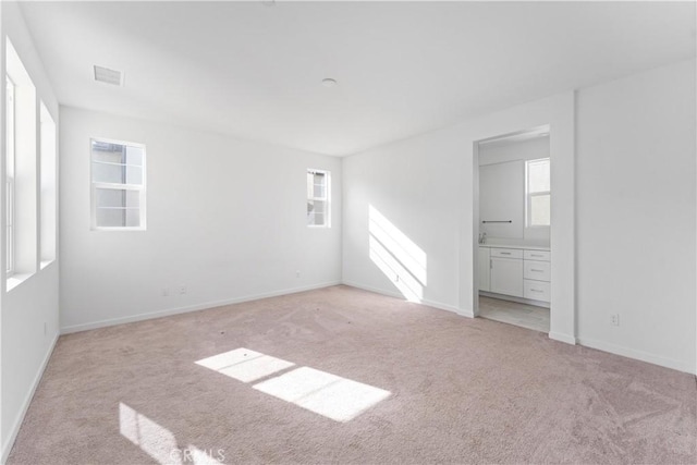 unfurnished bedroom featuring light carpet, multiple windows, and baseboards