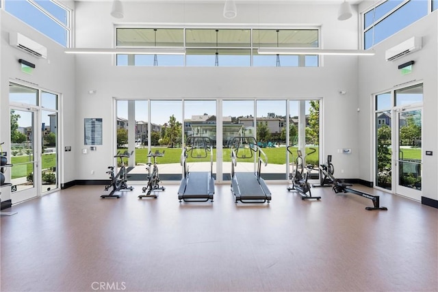 workout area featuring a towering ceiling, a wall mounted AC, and a wealth of natural light