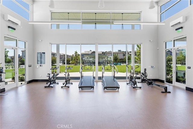 exercise room featuring baseboards, a high ceiling, and a wall unit AC