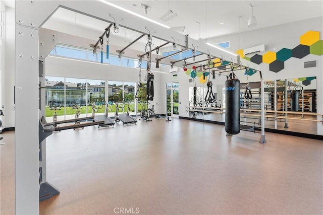 workout area featuring an AC wall unit, visible vents, and a high ceiling