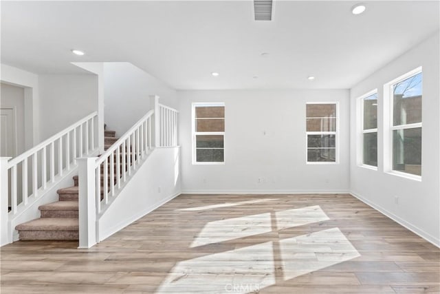 empty room featuring stairs, visible vents, recessed lighting, and light wood-style floors