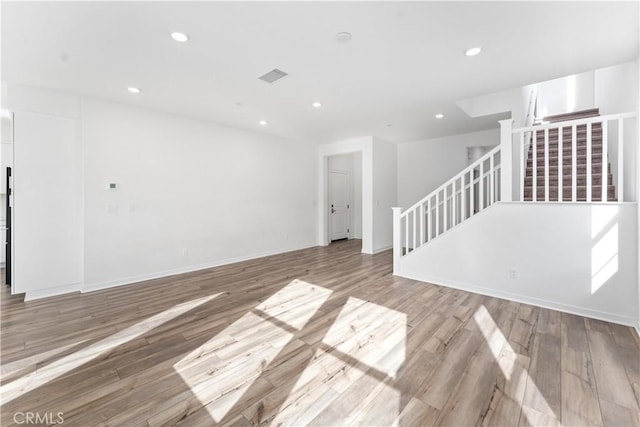 unfurnished living room with stairway, wood finished floors, visible vents, and recessed lighting