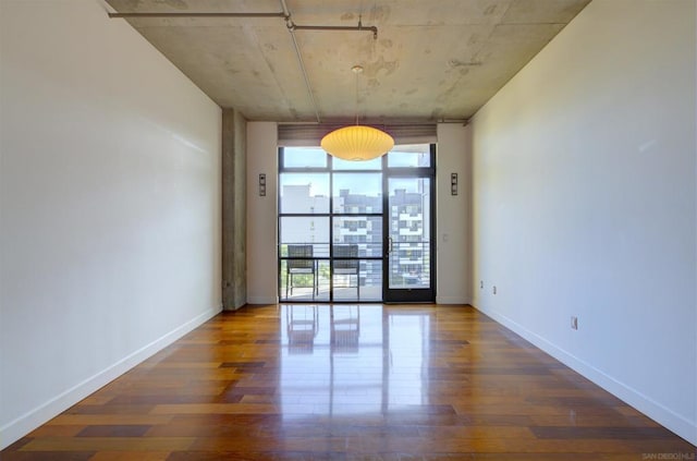 spare room with a wall of windows and dark hardwood / wood-style floors