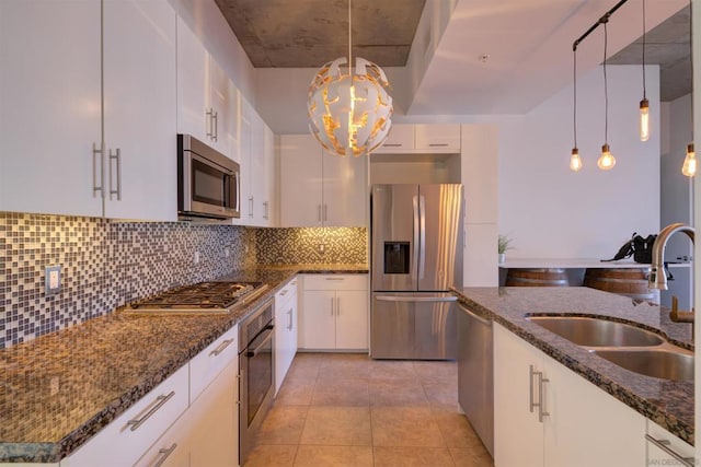 kitchen featuring white cabinetry, appliances with stainless steel finishes, decorative backsplash, decorative light fixtures, and sink