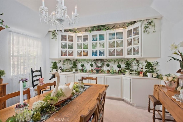 dining room with light colored carpet, lofted ceiling, and an inviting chandelier