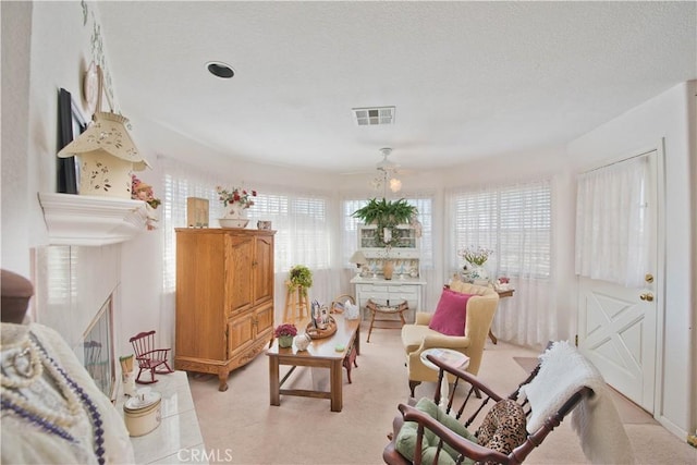 living area with ceiling fan and a textured ceiling