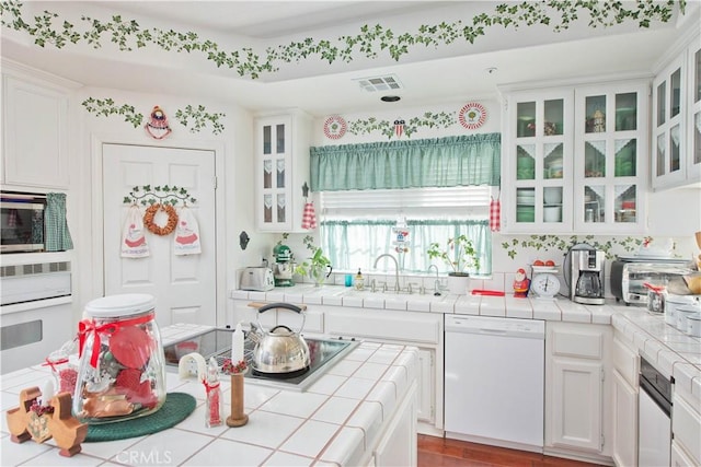 kitchen featuring white cabinets, tile counters, and white appliances