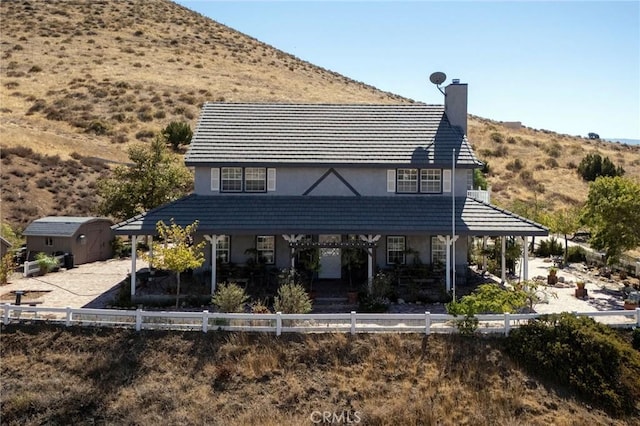 rear view of property featuring a storage unit and a mountain view