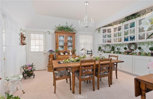 carpeted dining area featuring a chandelier and vaulted ceiling