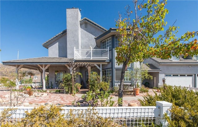 back of property with a garage and a balcony