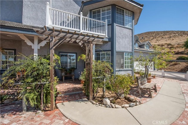 view of exterior entry with a patio area and a balcony