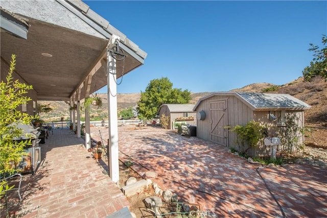 view of patio / terrace with a mountain view and a shed