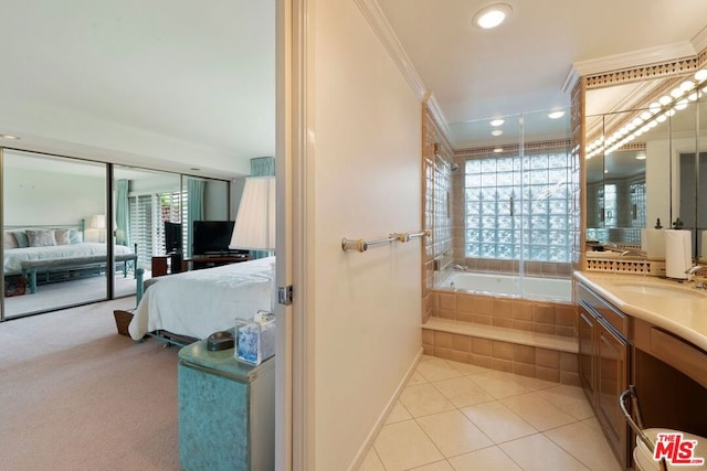 bathroom featuring a relaxing tiled tub, vanity, crown molding, and tile patterned floors