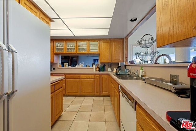 kitchen featuring light tile patterned flooring, white appliances, and sink