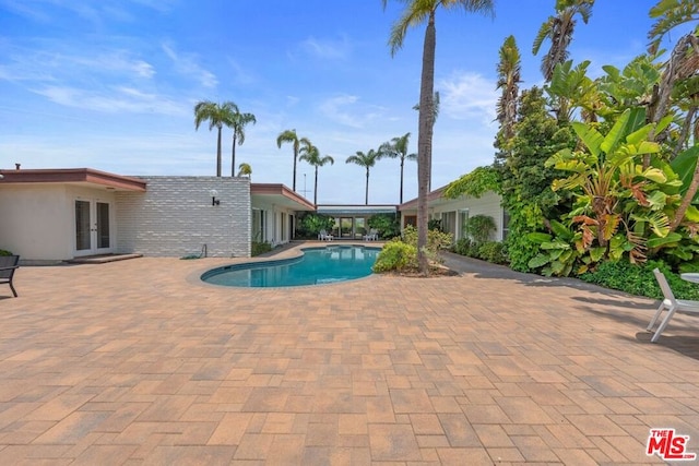 view of pool with french doors and a patio