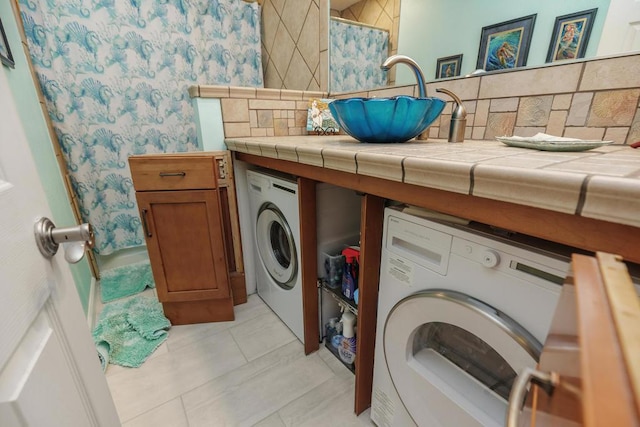 washroom with light tile patterned flooring, washer / clothes dryer, and sink