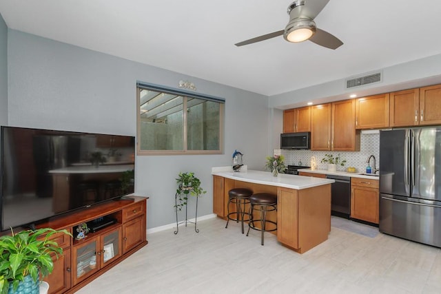 kitchen with stainless steel appliances, decorative backsplash, sink, kitchen peninsula, and a breakfast bar area