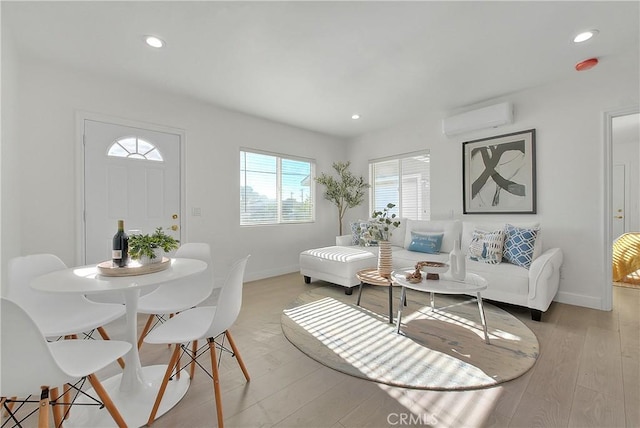 living room with an AC wall unit and light hardwood / wood-style flooring