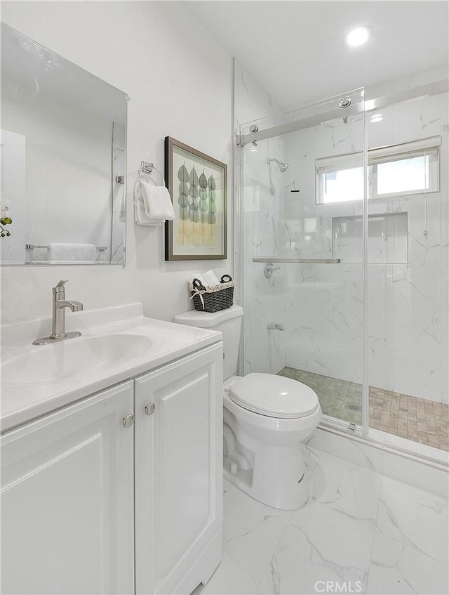 bathroom featuring a shower with door, vanity, and toilet