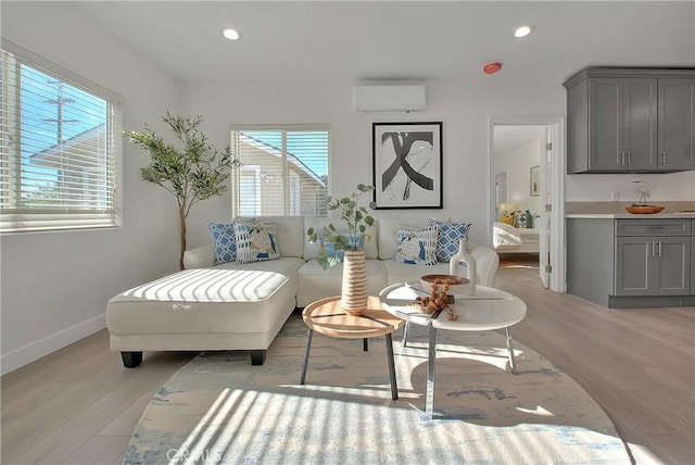 sitting room featuring a wall mounted AC, light wood-type flooring, and plenty of natural light