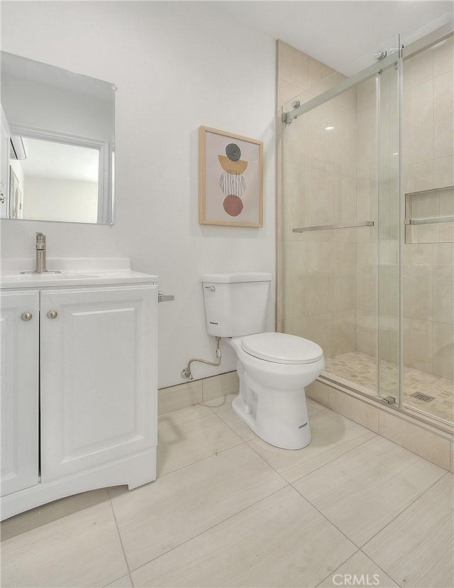 bathroom featuring tile patterned flooring, vanity, toilet, and a shower with shower door