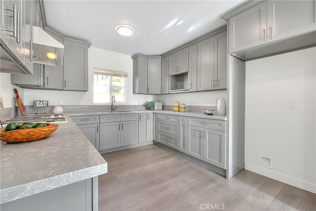 kitchen with gray cabinetry, light wood-type flooring, sink, and stainless steel gas cooktop