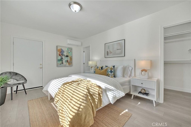 bedroom featuring a wall unit AC, a closet, and light wood-type flooring