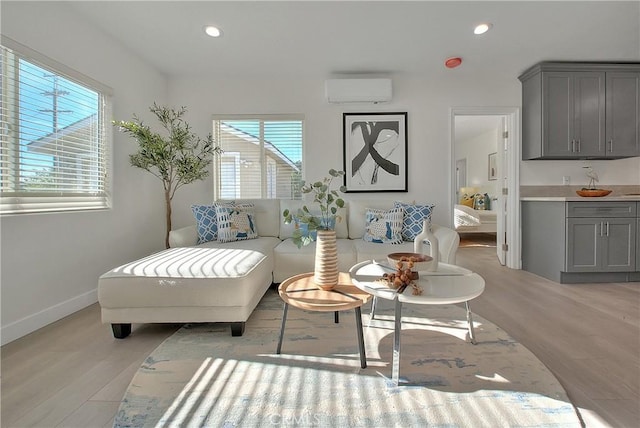 living area with a wealth of natural light, light hardwood / wood-style flooring, and a wall mounted air conditioner